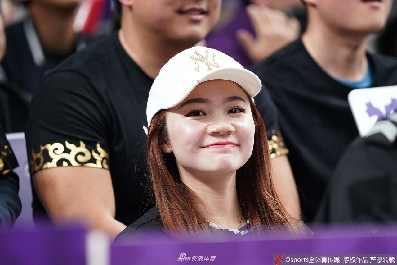 镜头捕捉到一位穿着时尚的女生，她手拿CBA官方吉祥物，脸上画着彩绘，对着镜头大方地展示自己，仿佛在用全身的细胞宣告着她对主队的绝对支持。