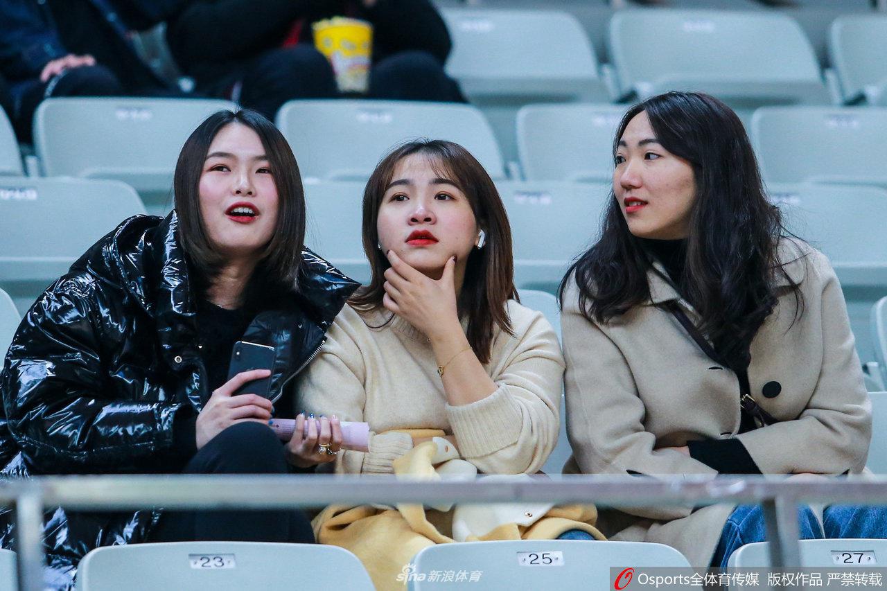 美女球迷和身边的朋友交流,她轻轻撩动发丝,流露出自然随性的美感。