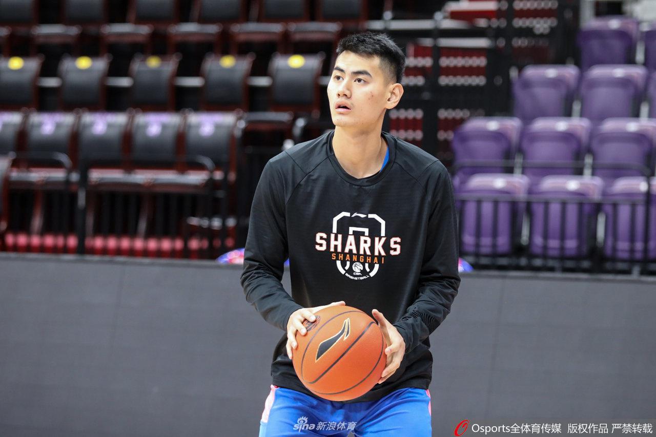 队长张兆旭在训练间隙与队友交流心得，高大的身影在夕阳的余晖下拉长，彰显出球队内部的团结与凝聚力。