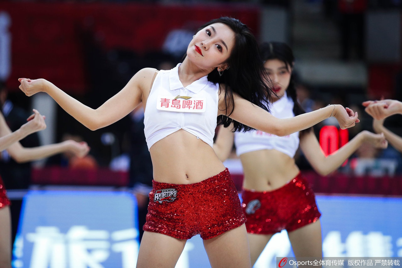 侧方机位捕捉到群舞高潮,数位宝贝瞬间腾空跃起发丝飞扬,粉白相间的队服在灯光下划出优美弧线,动感张力穿透屏幕