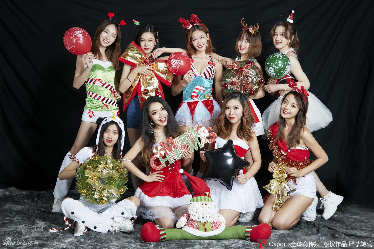 身披红白节日盛装的啦啦队宝贝，手拿金色花球，在聚光灯下回眸一笑，眼神中透出节日的喜悦与青春的灵动。