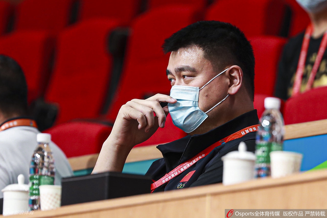 身着一袭深色便装的姚明，双手轻轻交叠置于膝前，那高出人群的独特身影在赛场边显得格外醒目，他神情专注而平和，宛如一座静默的山峦，注视着场上的风云变幻。