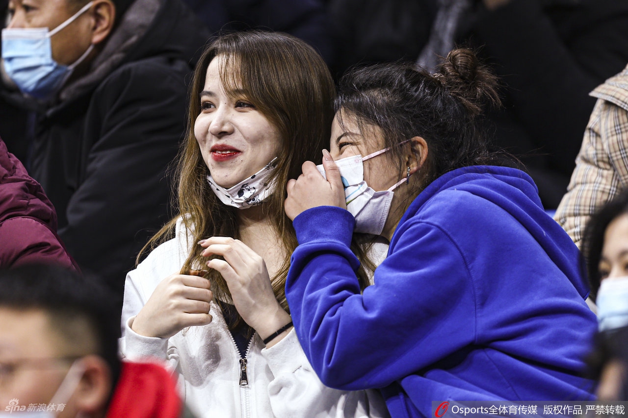 镜头聚焦在一名戴着眼镜的斯文女球迷脸上，她神情专注地看着场内，微微张开的双唇似乎随时准备为一次精彩抢断而惊呼，那股投入的劲儿，完全不输给身边任何一位资深男球迷。