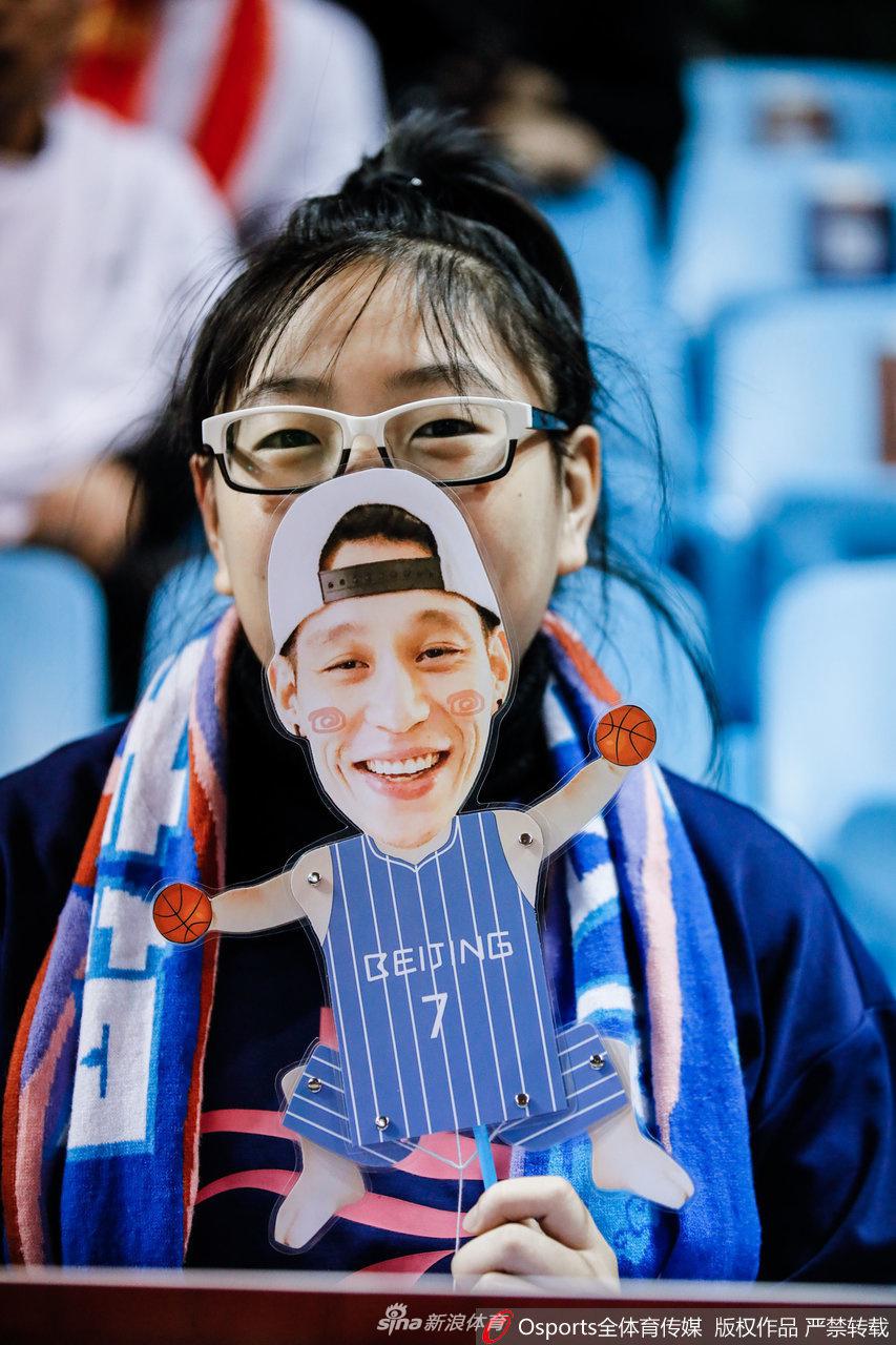 一名戴着首钢队帽的漂亮女球迷，在比赛暂停期间转身自拍，她的脸上贴着一枚小小的北京队队徽，眼神中流露出对球队的无限眷恋与支持。