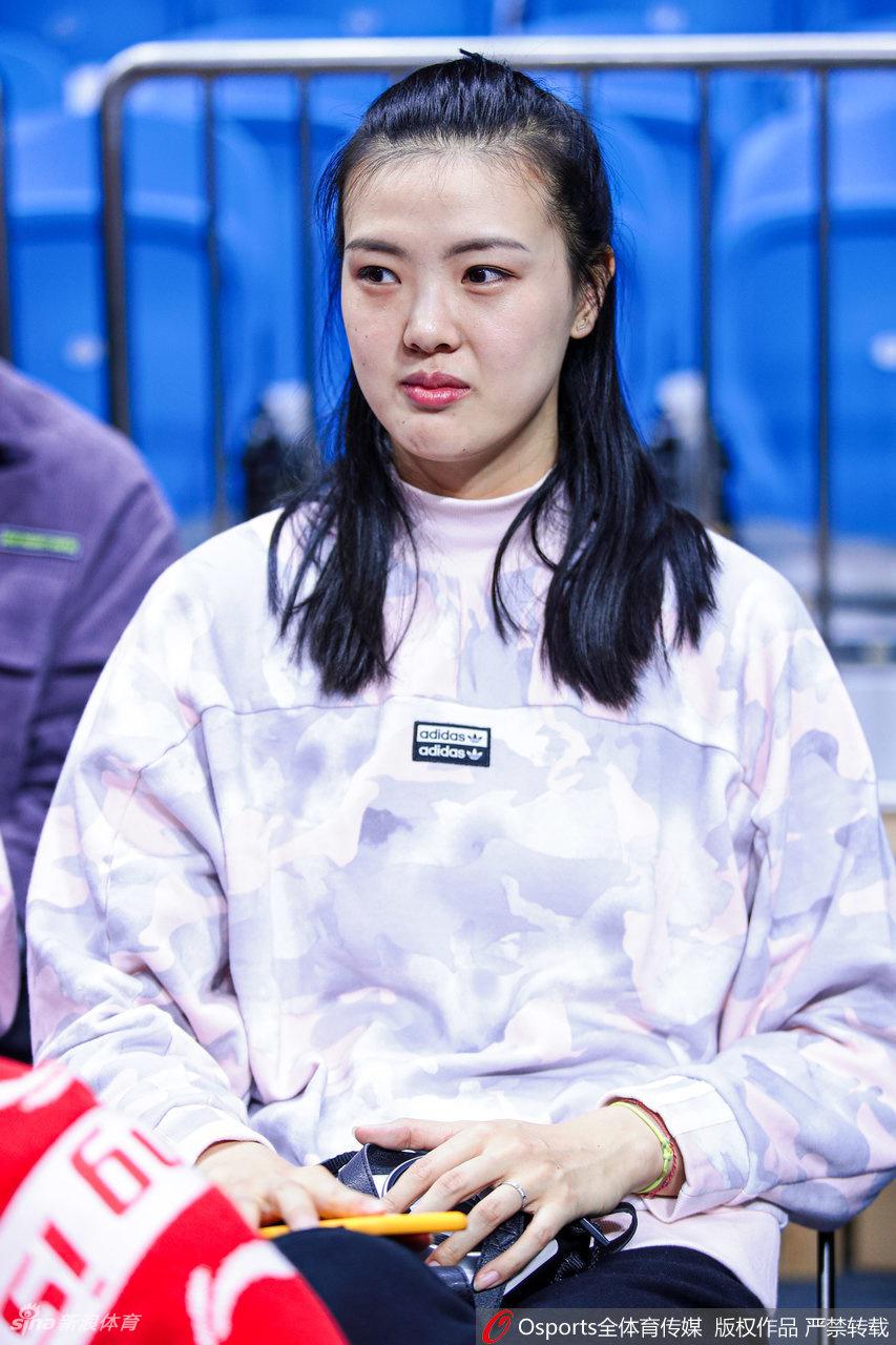 陈露与友人一同出现在观众席，她对着镜头大方微笑，自信从容。身后的赛场灯光璀璨，映衬出这位前世界冠军与时尚辣妈的双重魅力。