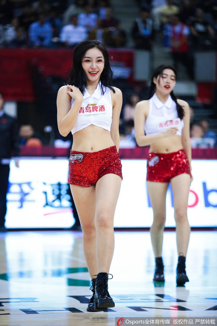 全队背对镜头向看台挥手致意,她们修长的身姿在顶光下拉出影子,手中挥舞的花球闪烁金色彩带,将全场氛围推向最高潮