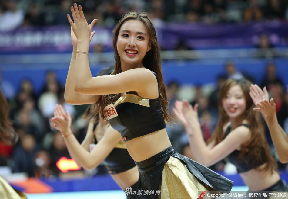 镜头拉近,一位篮球宝贝对着观众席甜美比心,修长的睫毛和精致的妆容清晰可见,身后的巨大记分牌记录着比赛的激烈进程。