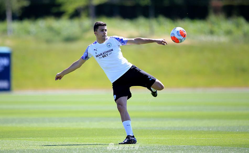 多名曼城球员在教练的指挥下分成两队进行拉伸练习，大家错落有致地保持距离，阳光在湿漉漉的草地上投下长长的影子，像是一组跃动的音符谱写着复工的序曲。