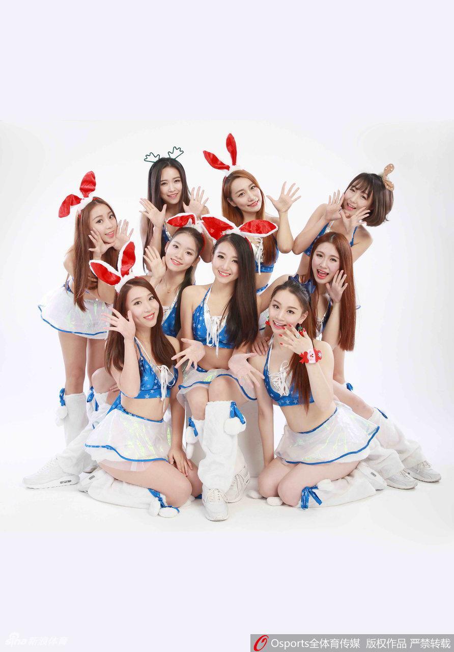 一位宝贝坐在场边的圣诞礼盒装饰旁，手捧迷你圣诞树，修长的身姿与甜美的长相构成一幅动人的节日画卷。