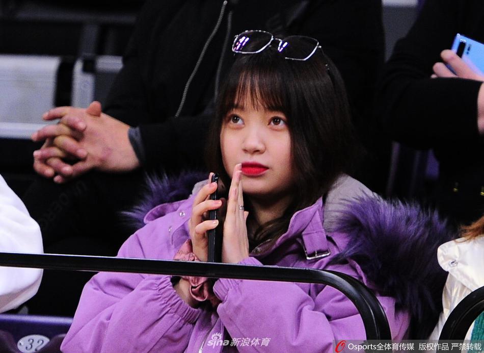 看台上，一位长发披肩的姑娘身着时尚的格子大衣，在人群中格外抢眼。她目光专注地凝视着赛场方向，双手高高举起手机，想要定格下偶像郭艾伦驰骋赛场的英姿，这画面本身就是一道最美的风景线。