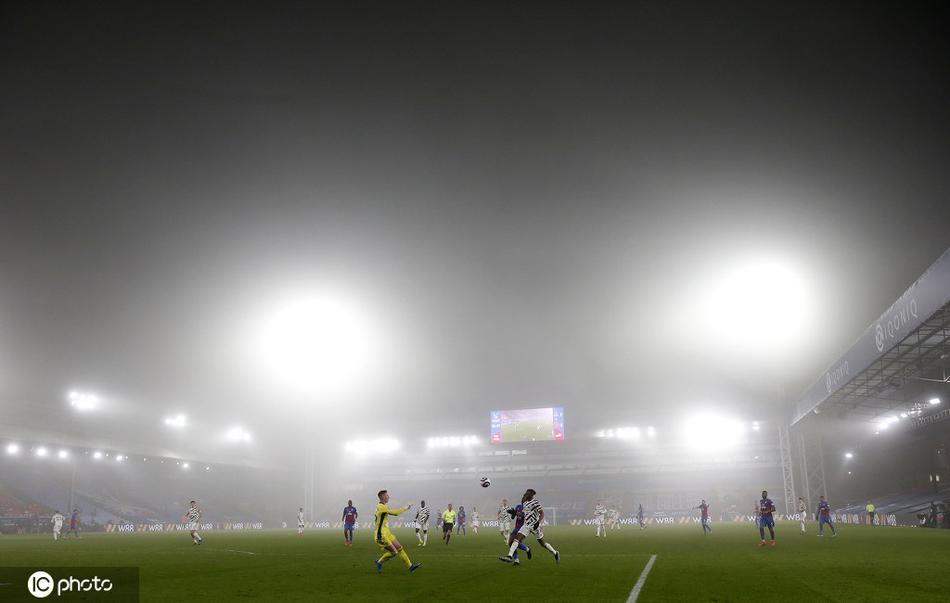 从球门后方望去，大雾彻底模糊了球场的另一端，球门后的看台结构在雾中仅剩下几何线条，整个场景静谧得如同黎明前的空灵幻境。