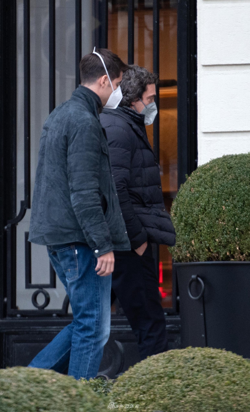 两人在建筑物前停下脚步，莫拉塔双手插袋，望向远方，经纪人在侧，一幅共同面对未来的画面。