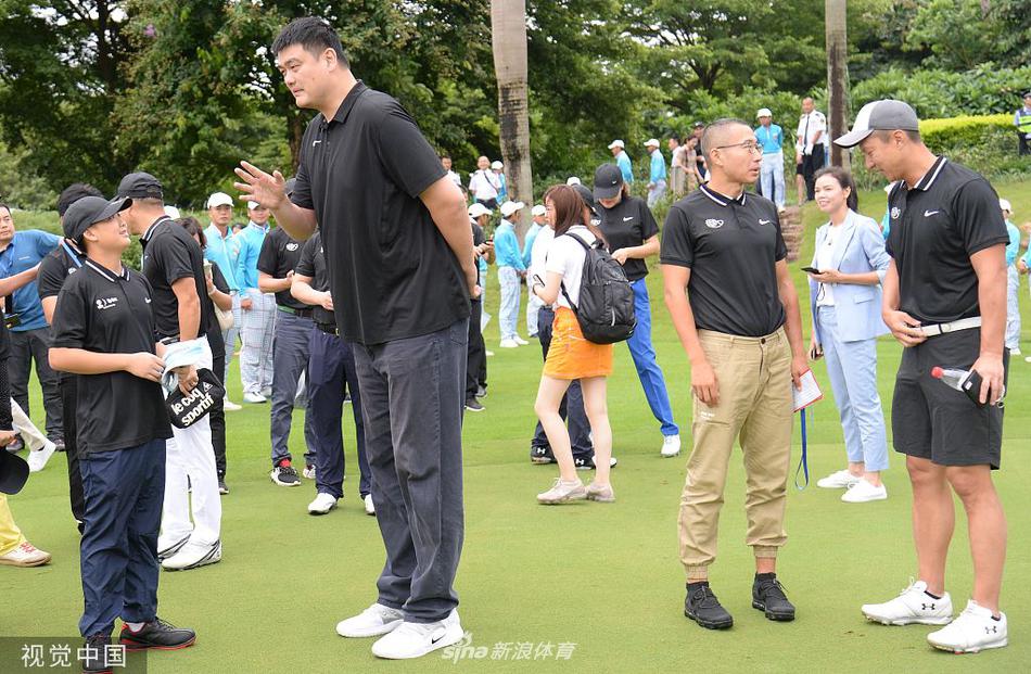 绿茵场上,姚明双手扶着推杆,全神贯注地瞄准球洞,动作虽显生涩却极为认真,周围观众的目光都聚焦在这位篮球巨星的高球首秀上