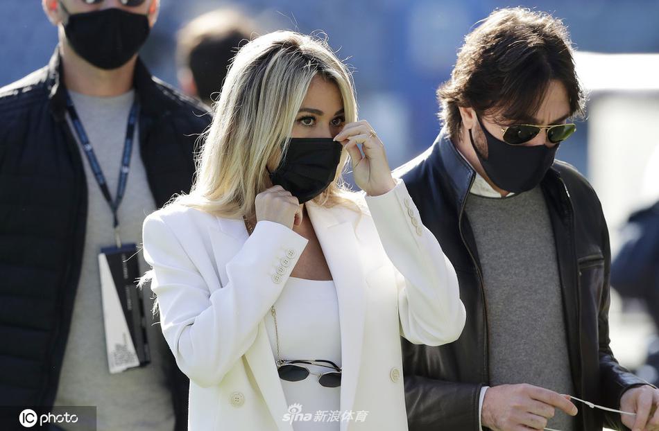 远景下的莱奥塔站在场边，尽管距离遥远，但她高挑的身形和独特的时尚品味依然让她在人群中脱颖而出，成为焦点。