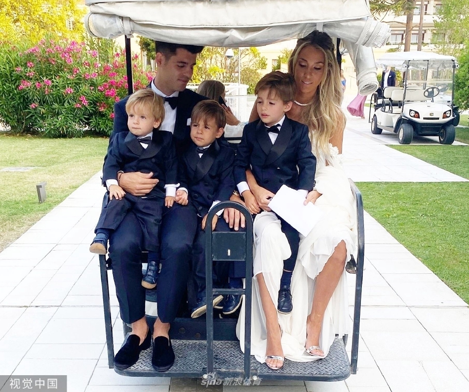 仪式间隙的轻松时刻，莫拉蒂俯身与儿女嬉戏交谈，孩子们仰头听着，画面生动有趣，展现了奢华礼服之下自然温暖的亲情互动。