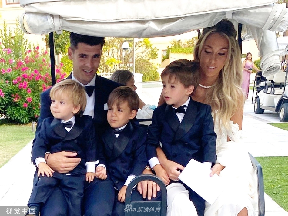 加布里埃莱·莫拉蒂与妻子深情相拥于威尼斯河道旁，妻子身着一袭简约而优雅的白色礼服，与丈夫的深色西装相映成趣，远处古老的建筑与荡漾的水波为这一刻的浪漫定格。