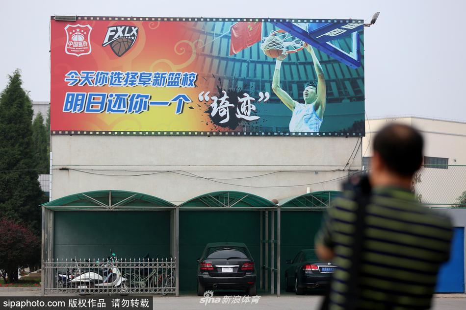 夏日午后，阜新篮球学校训练馆内，阳光透过高窗洒在光亮的地板上，几名小球员正在挥汗如雨，墙上的大幅励志标语与周琦的照片遥相呼应，仿佛在诉说着这里代代相传的篮球精神。