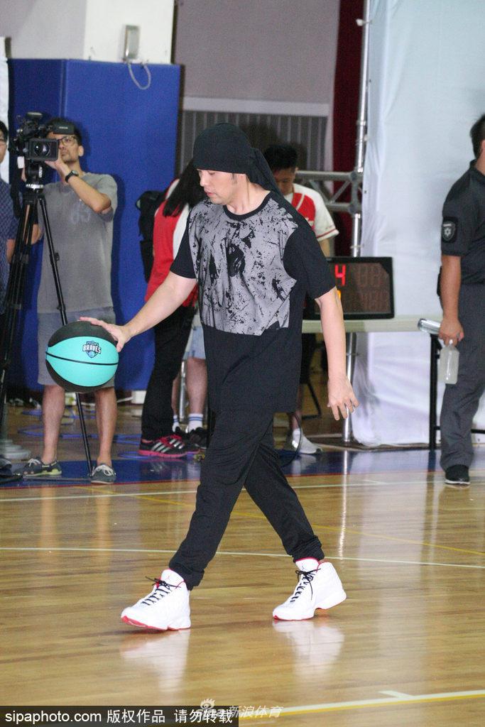 周杰伦在场上指挥跑位，他伸出手臂指向篮筐方向，头巾的结打在脑后，侧脸线条分明，神情专注而认真，完全沉浸在比赛的乐趣中。