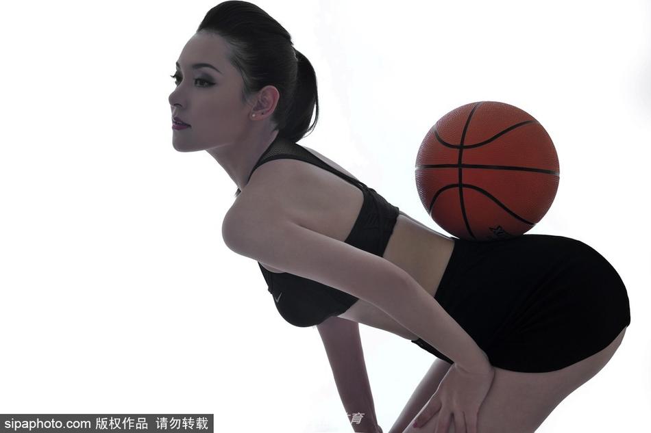 杨不悔倚靠在球场边的广告牌上，修长的双腿在灯光下格外引人注目，她双手轻轻撑在身后，姿态慵懒却散发着健康阳光的性感魅力。