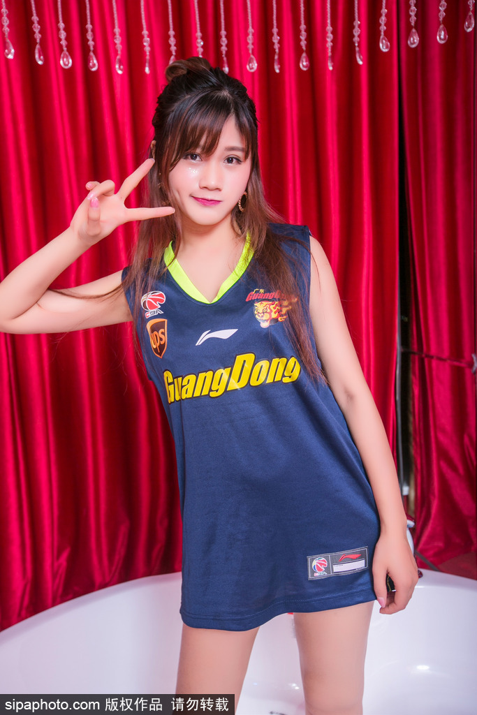 她跪坐在地，笑容甜美而治愈。简洁的运动背心展现出健康的力量感，整个画面洋溢着青春独有的朝气与美好，让人忍不住多看几眼。