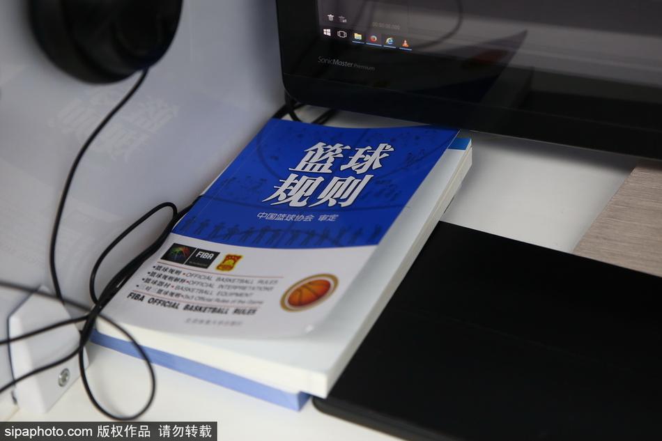 一位经验丰富的值班裁判神情专注,他面前的屏幕定格在一次激烈的篮下对抗瞬间,他正在通过耳麦与现场裁判进行沟通。