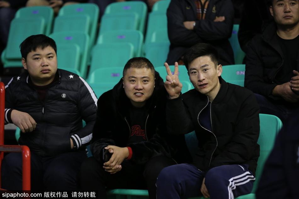 看台过道上，几位穿着奢华貂皮大衣的球迷并肩而立，其中一位女性球迷正挥手欢呼，厚重的皮草难掩她此刻因为主队领先而迸发的激情。