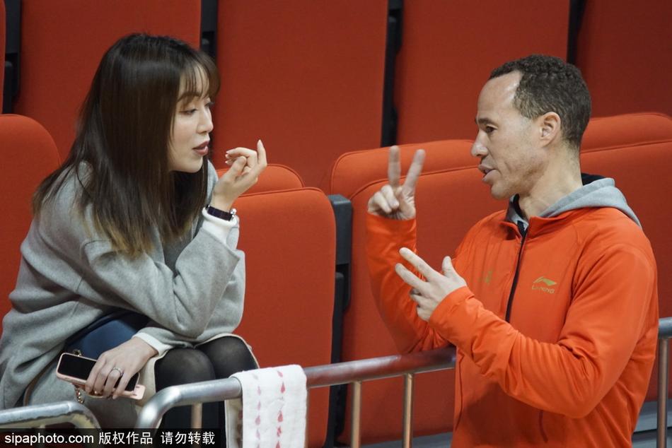 比赛进入暂停时间,美女裁判站在场边等待重新开球,她的背影与看台上密密麻麻的观众形成对比,红色的地板映衬着她的身姿,显得格外挺拔。