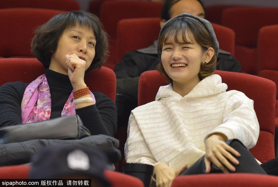 寒夜抵挡不住热情，一位身穿白色外套的山东美女球迷在加时赛关键时刻紧张起身，目光紧紧锁定场上的每一次攻防。