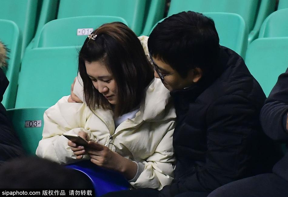 男球迷在万众瞩目下深情亲吻他的女友，女孩闭着眼沉浸在幸福中，背景是模糊的看台和CBA的广告牌，这一刻体育竞技的残酷被爱情的甜蜜温柔化解。