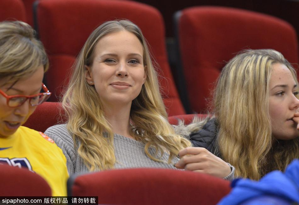 莫泰妻子在看台上与身边友人交谈,笑容温婉大气,金色的长发在灯光下熠熠生辉,尽显东欧女性的独特魅力