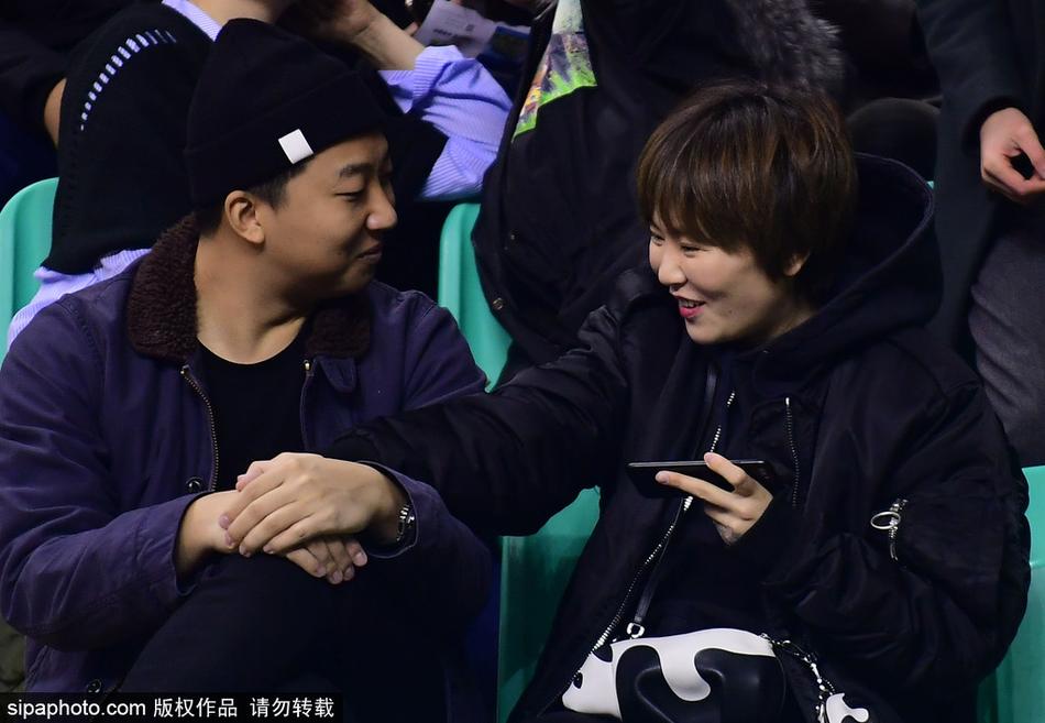 两人紧紧相拥在红色的座椅前，男生的外套上依稀可见支持辽宁队的标语，女生则将头深深埋在男友怀里，周围的球迷纷纷掏出手机记录这温馨的一刻。