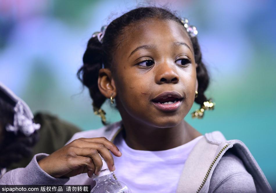 小女儿似乎有些困倦，小手托着腮帮子，但依然努力睁大眼睛望向场内，不想错过任何一秒爸爸在球场上的英姿。