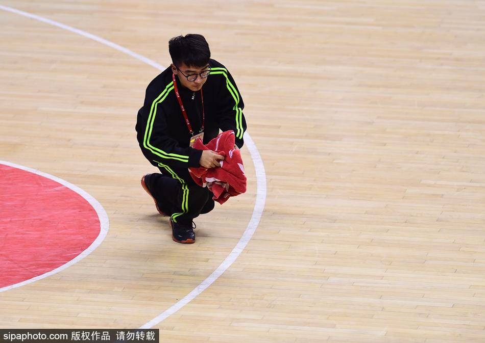 裁判与球员围成一圈争球瞬间,场边穿着橙色马甲的“地板工”手持毛巾安静等待,随时准备履行职责