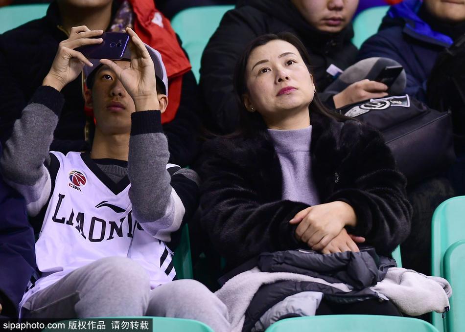 散场后的人流中,一位穿着貂皮大衣的球迷爸爸将孩子扛在肩上,孩子手里还拿着辽宁队的小旗子。寒冷的冬夜,父子的身影在路灯下被拉长,皮草的厚重与亲情的温馨交织,为这场篮球盛宴画上了一个温暖的句号。
