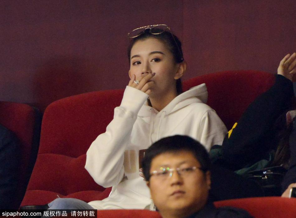 一位美女球迷在人群中回眸,自信地面对镜头,她的眼神清澈而坚定,展现出当代女性球迷的独立风采。