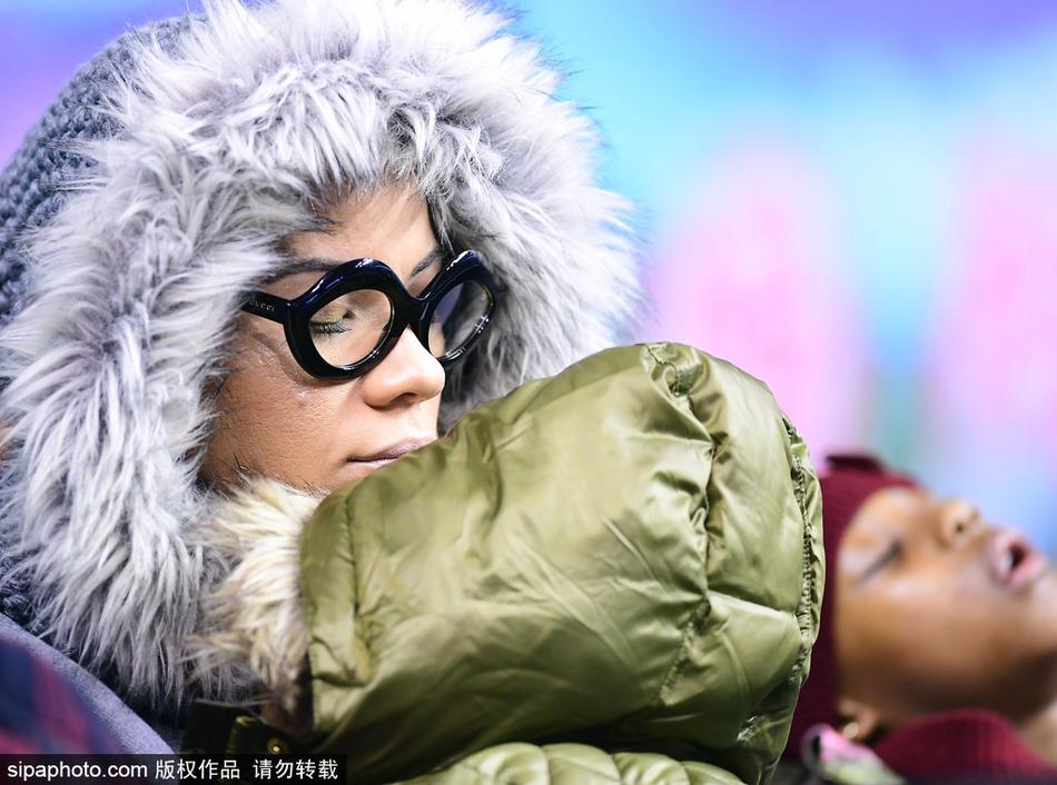 哈德森妻子面带微笑，眼神温柔地看着怀里的女儿。即使在嘈杂的体育场内，母女二人也自成一方宁静的小天地，仿佛时间都为此放缓了脚步。