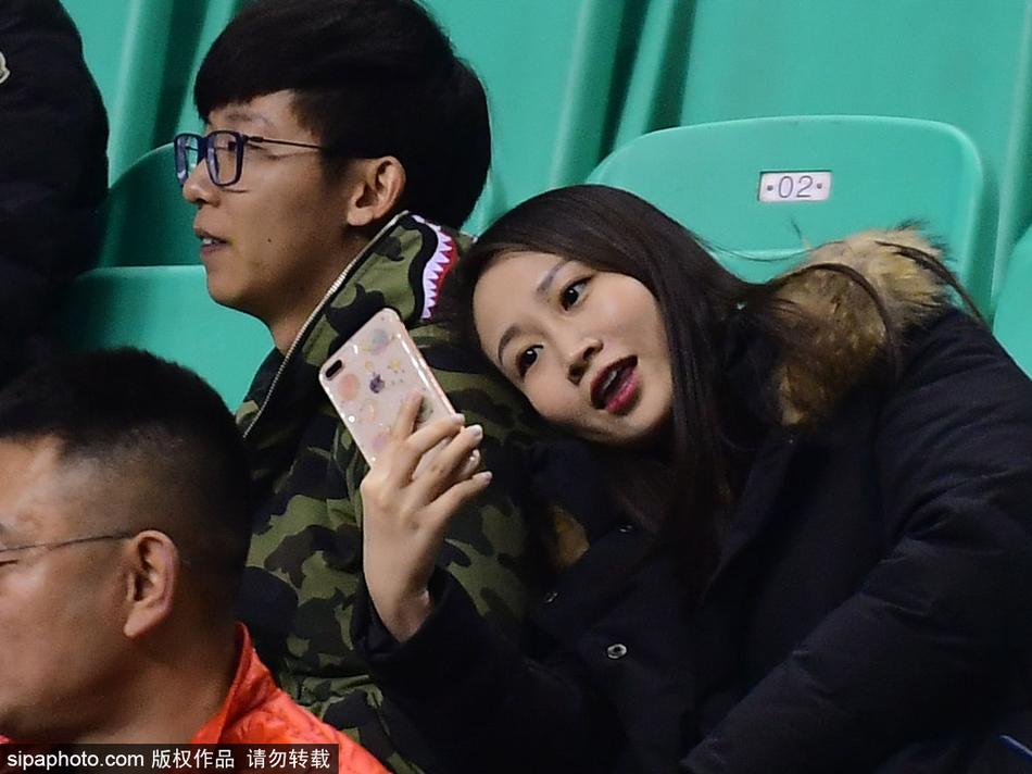 在辽宁本溪热烈的CBA赛场中央，一位身穿羽绒服的男球迷双手捧着女友的脸庞，两人额头相抵，眼神中充满爱意，全然不顾四周震耳欲聋的呐喊声，仿佛整个世界只剩下彼此。