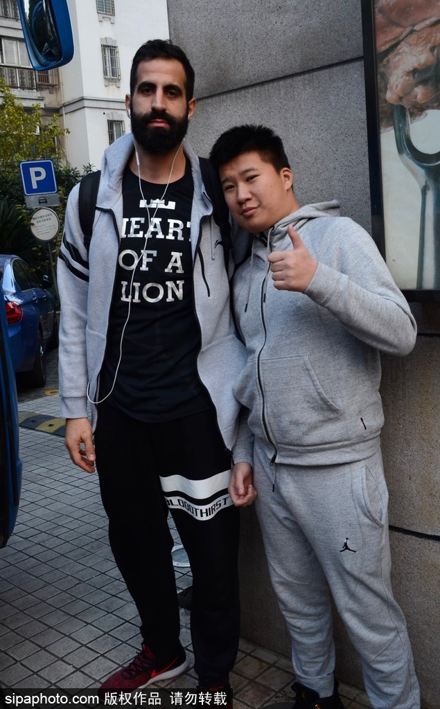 汉斯布鲁在酒店大堂为球迷耐心签名，眼神专注，身后球迷兴奋地展示签名战利品