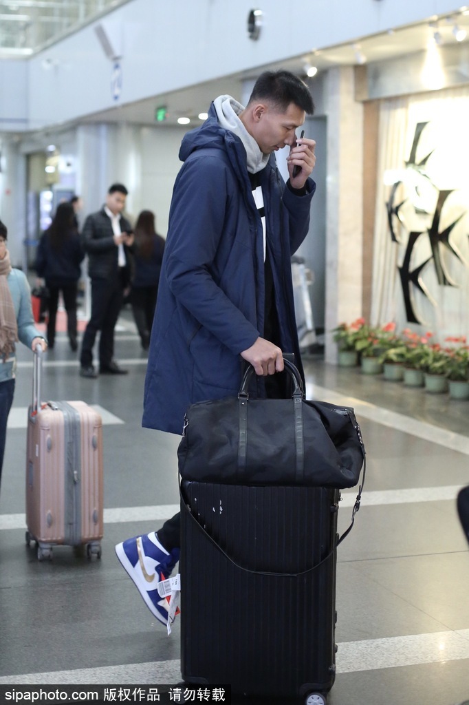易建联身穿深色潮流外套搭配个性背包，在机场通道中回眸一瞥，眼神中既有运动员的坚毅又不失时尚达人的洒脱