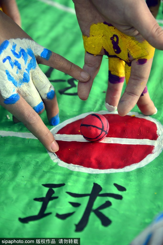 镜头拉近,可以看到‘球员’其实是用面团捏成的小人,安静地站在用纸板画成的球场上。而真正的‘运动员’——学生的手指,已经涂上了鲜艳的颜色,正准备登场,一动一静之间充满了童趣与想象力。