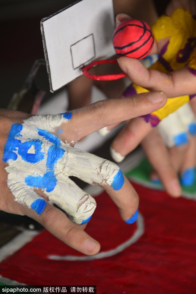 一位学生正全神贯注地盯着指尖下的‘篮球赛场’,他微微弯下腰,用涂了颜色的手指灵活地‘运球’突破,脸上的表情既认真又带着忍俊不禁的笑意,仿佛正在进行一场真正的NBA总决赛。