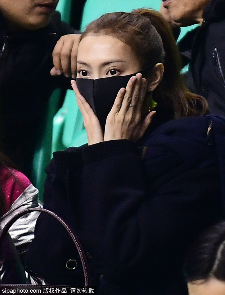 李旭在人群中回眸一笑,面容精致清秀,她身着一袭时尚外套,在喧嚣的球场看台上显得格外亮眼夺目。