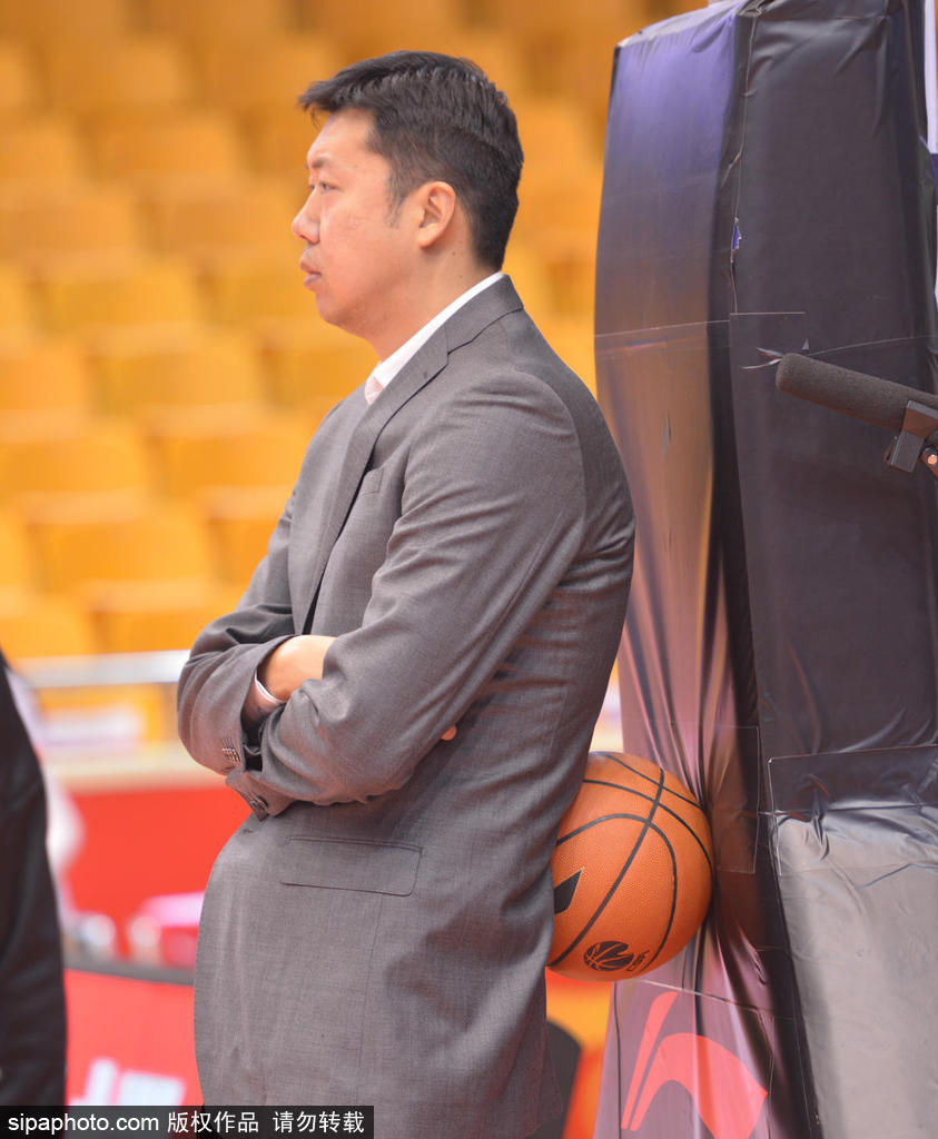 王治郅近距离观看球员热身，他高大的身影在人群中格外显眼，身旁的球员正在进行上篮练习，大郅的目光紧紧跟随篮球的轨迹。