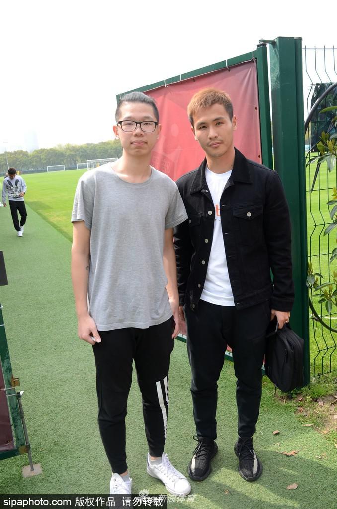 上海上港球星训练后身着潮流便装，尽显挺拔身姿与帅气型男本色，面对球迷签名请求露出温暖笑容。