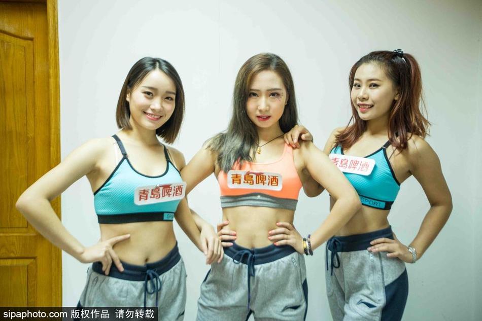 在略显拥挤但充满欢声笑语的更衣室里，篮球宝贝们正围坐在一起，全神贯注地对着镜子勾勒妆容，为即将开始的表演做最后准备。