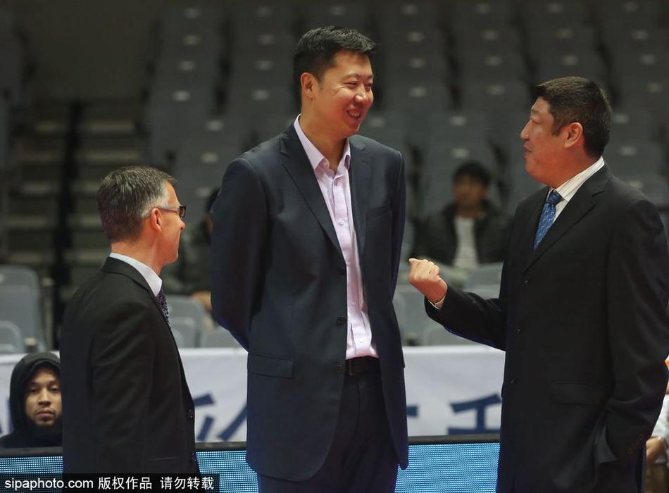 赛前热身区域，王治郅与江苏同曦队的一名年轻球员击掌问候，脸上洋溢着温暖而谦逊的笑容，毫无传奇球星的架子。