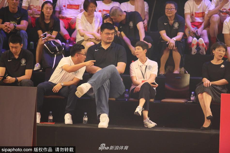 姚明手持篮球仔细观察，身旁的奖杯熠熠生辉，仿佛在传递着对草根冠军的致敬