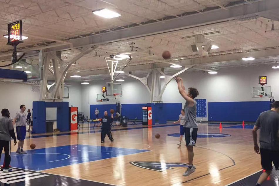 丁彦雨航双手抱球置于腰间，身穿白色小牛队训练背心，在训练馆的蓝色背景板前留下定妆照，眼神坚定地望向前方