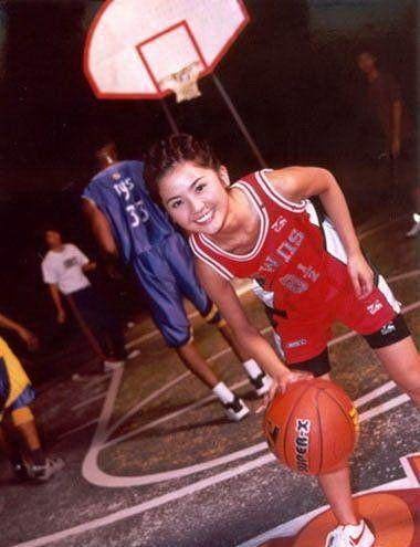 特写镜头中，女孩头戴针织帽，篮球背心的宽松轮廓与手腕上的配饰细节形成对比，她的眼神清澈而坚定，展现了篮球背心穿搭的街头潮流感。