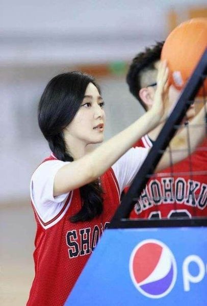 暖色灯光下，女孩身着篮球背心静坐，宽松的衣摆下是纤细的四肢，她手扶帽檐，神情若有所思，将运动装的活力与居家的宁静完美融合。